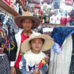 Batik fabrics & carved wooden figures in a market also selling local fruit